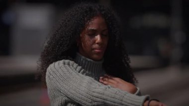 Kıvırcık saçlı genç bir kadın, süveter giyiyor, dans antrenmanı yapıyor açık havada, yetenek ve zarafet gösteriyor.