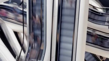 Yürüyen yürüyen merdivenlerdeki insanlarla dinamik alışveriş merkezinin görsel temsili, modern kentsel yaşam tarzını yansıtıyor