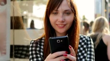 Şehir ortamında akıllı telefon kullanan bir kadın, açık hava iletişimi ve dijital ilişkiden zevk alıyor.