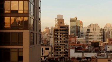 Günbatımında modern binalar ve yüksek binalarla şehir manzarası, pencerelere yansıyor, kentsel yaşamı ve mimariyi yakalıyor