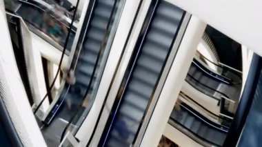 Çoklu yürüyen merdivenleri, çelik yapıları ve cam panelleri olan modern bir alışveriş merkezi ziyaretçilere dinamik bir manzara sunuyor