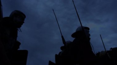 Şafak vakti karamsar gökyüzüne karşı antenleri olan siluetli figürler, bir huzur ve beklenti anı yakalıyorlar..