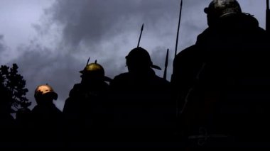 Mızraklı ve miğferli siluetli savaşçılar dramatik bir alacakaranlıkta yoğun ve tarihi bir sahne yaratıyorlar..