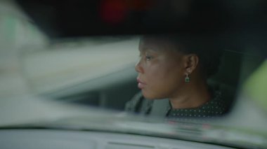 Bir kadın derin düşüncelere dalarken ya da bulanık bir pencereden görüldüğü gibi odaklanırken arabasını sürerken yakalanır..