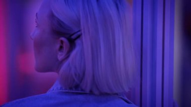 Şehir ortamında parlak neon ışıklarla aydınlatılmış kısa sarı saçlı bir kadının arka planı..