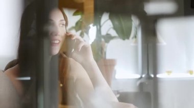 Telefondaki kadın, ev ofisinden çalışıyor. Kapalı alan bitkisi. Rahat atmosfer, modern çalışma alanı.