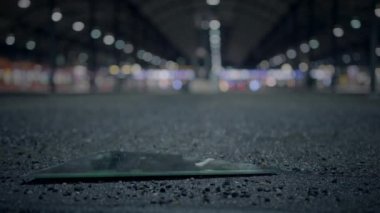 Kırık bir cam parçası boş bir şehir sokağında duruyor. Arka planda bulanık şehir ışıkları var..