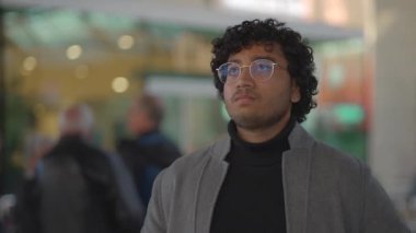 İçeride, gözlüklü ve kıvırcık saçlı genç bir profesyonel kendinden emin ve odaklanmış görünüyor.