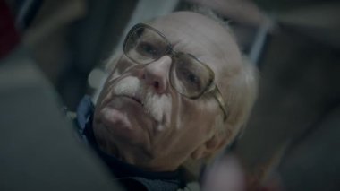 Gözlüklü, bıyıklı, derin derin düşünen, bilgelik ve deneyim saçan yaşlı bir adamın yakın çekimi.
