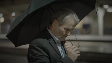 Takım elbiseli bir işadamı, bir tren istasyonunda şemsiyenin altında, şehrin ortasında dalgın dalgın dalgın dalgın dalgın dalgın dalgın dalgın dalgın dalgın dalgın dalgın,