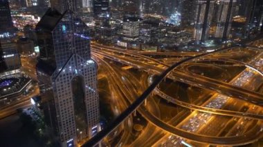 Aydınlatılmış otoyollar ve gökdelenler, modern altyapıyı ön plana çıkaran bir kentsel gece sahnesi sunar
