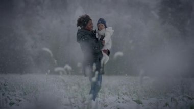 Ebeveyn ve çocuk, kış harikalar diyarında, karlı ormanda birbirlerini kucakladıkları bir anı paylaşıyorlar.