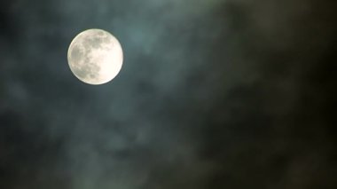Parlak bir dolunay bulutlu, mistik bir gece gökyüzünde parlıyor, huzurlu ve büyülü bir ortam yaratıyor..