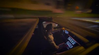 Yetenekli bir sürücü güzel aydınlatılmış şehir sokaklarında geceleri heyecan verici bir manzarayla ustaca gezinir.