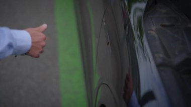 Park halindeki bir arabanın yanında duran bir kişi park yardım tekniklerini gösteriyor..