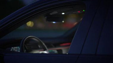 Bu, gece vakti bir arabanın içindeki yakın çekim görüntüsü, direksiyonu ve çevresindeki aydınlatmayı vurguluyor.