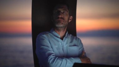Bir adam okyanusun kenarında duruyor, içini huzur ve yansıtmayla dolduran güzel bir günbatımına bakıyor.