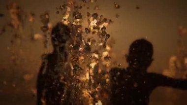 Çocuklar gün batımında parıldayan suda oynarken ve gülerken çekilen neşeli ve keyifli anlar.