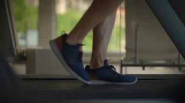 Spor ayakkabılarının koşu bandında aktif olarak kullanıldığı yakın plan görüntüsü, spor ve fiziksel aktiviteyi sembolize eder