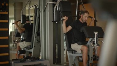 Bir adam, çağdaş ve iyi donanımlı bir spor salonu ortamında güçlü eğitim egzersizleri yapıyor.