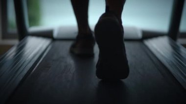 Koşu bandında hızla koşan ayakların yakından çekimi, spor yapmayı, araba kullanmayı ve kararlılığı sembolize ediyor.