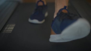 Koşu bandında egzersiz yapan, spor ayakkabıları ve sağlıklı bir yaşam tarzını destekleyen yakın plan.