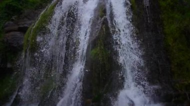 Nefes kesen bir şelale engebeli kayalıklarda zarifçe süzülüyor, yemyeşil ve canlı yeşilliklerle çevrili.