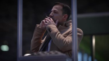 Bir adam, gece saatlerinde bir telefon kulübesinde önemli bir telefon görüşmesi yapar.