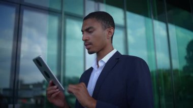 Oldukça odaklanmış bir profesyonel canlı bir şehir ortamında parlak bir tablet cihazıyla aktif olarak meşgul oluyor.