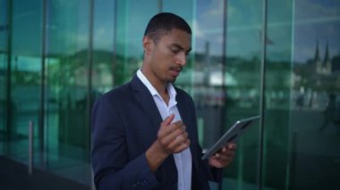 Modaya uygun ve şık bir adam, çağdaş bir şehir ortamında bir tablet cihazıyla aktif olarak meşgul oluyor.