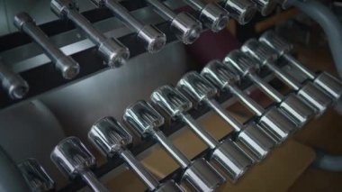 Parlak dambılların yakın plan görüntüsü titreşimli bir fitness ortamındaki raflarda güzelce düzenlenmiştir.