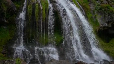Nefes kesen güzel bir şelale engebeli kayalık arazide zarifçe süzülüyor, canlı yeşil yosunlarla kaplanıyor.