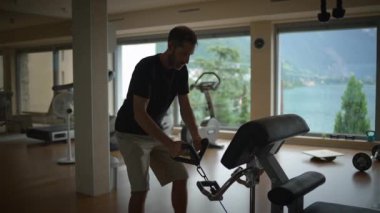 Bir adam, göz kamaştırıcı ve fotojenik doğal bir arkaplanı olan iyi ışıklandırılmış bir spor salonunda güç eğitimi alıyor.