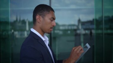 Bir işadamı, modern profesyonelliği somutlaştıran gösterişli bir ofis ortamında dijital tabletle uğraşır..