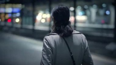 Şık kıyafetli bir kadın, canlı şehirde gece dolaşır, şehir yaşam tarzını ve modasını somutlaştırır.