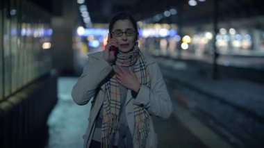 Kentsel bir gecede telefonuyla yoğun bir şekilde konuşan bir kadın, gözle görülür şekilde sıkıntılı ve endişeli görünüyor.