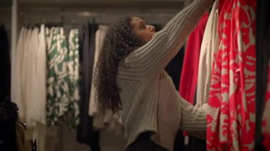 Bir kadın şık ve şık bir perakende mağazasında satılan şık giyim seçeneklerini inceliyor.