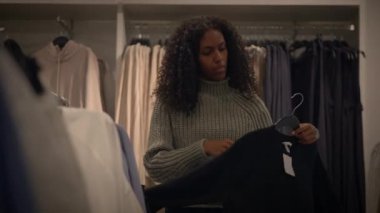 Modaya uygun bir kadın modern bir perakende piyasasında çeşitli giyim seçeneklerini gözden geçiriyor.