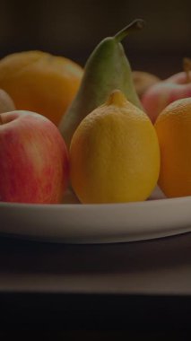 Taze, sulu elmalar, tatlı armutlar ve saf beyaz bir tabakta keskin limonlar içeren renkli ve canlı bir ekran.