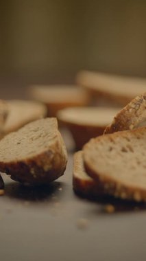 Dilimlenmiş zanaatkar ekmeği rustik ahşap bir masa üzerinde gelişigüzel düzenlenir, dokusunu ve kabuğunu güzelce gösterir.