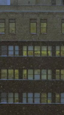 Göz kamaştırıcı güzellikte bir gece manzarası. Karla kaplı bir şehir binası. Parlayan, sıcak pencerelerle süslenmiş.