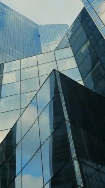 Gökyüzünü yansıtan açısal cam gökdelenlerin çarpıcı manzarası, tüm ihtişamıyla modern mimariyi sergiliyor.