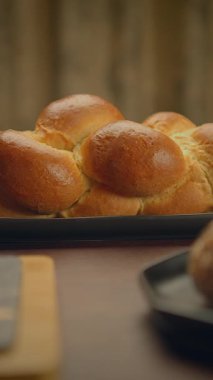 Güzel, altın örülmüş bir challah ekmeği dikkatle sade bir ahşap masaya dizilmiş, şenlikli toplantılar için ideal.