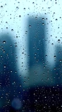 Bulanık bir şehir silueti yağmurlu camlardan görünür, rahatlatıcı ve sakin bir şehir atmosferi yaratır.