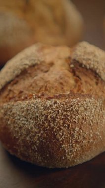 Güzel pişmiş yuvarlak bir zanaatkar ekmeği kabuklu kabuğunu ve içindeki sağlıklı taneleri sergiliyor.