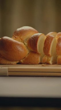 Bu altın örgülü ekmek çok güzel dilimlenmiş ve ahşap bir tahtanın üzerinde servis edilmiş. Her yemek için mükemmel.