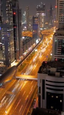 Çarpıcı bir gece manzarası aydınlatılmış otoyolları ve etkileyici modern mimarisi olan hareketli bir şehir manzarası sergiliyor.