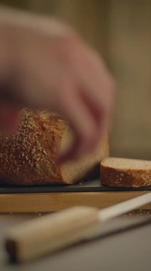 Zanaatkar bir ekmek somunu, kırsal bir tahta üzerinde, yemek fotoğrafçılığı için ideal bir dilimin yanında sanatsal olarak sergilenir.