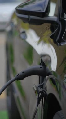 Ayrıntılı bir yakın çekim görüntüsü, bir arabaya güvenli bir şekilde bağlı olan elektrikli araç şarj bağlantısını gösterir