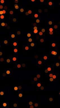 Ilık turuncu ve koyu kırmızı ile koyu arkaplandaki Bokeh ışıklarının büyüleyici soyut bir görüntüsü.